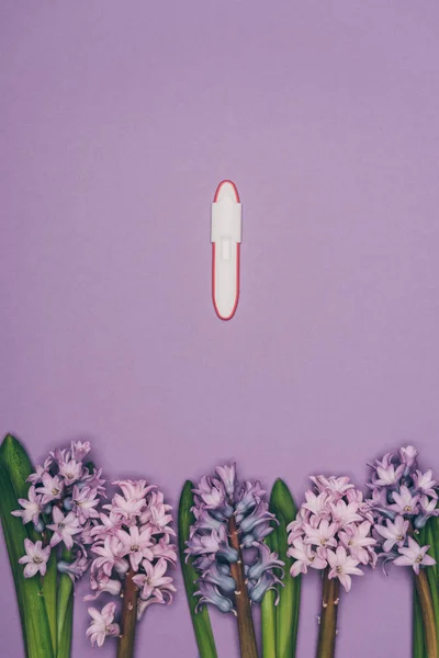 Top view of arranged flowers and pregnancy test isolated on purple — Stock Photo