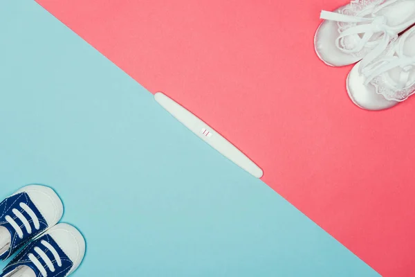 Top view of arrangement of  childish shoes and pregnancy test — Stock Photo