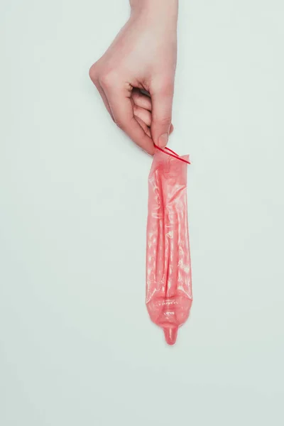 Vista parziale di donna tenuta aperto preservativo in mano isolato su grigio — Foto stock