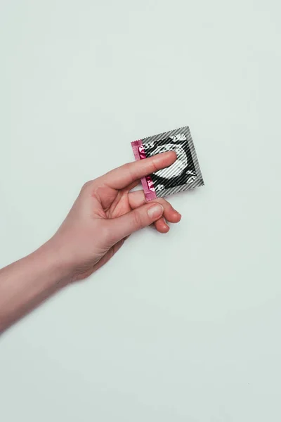 Cropped shot of woman with condom in hand isolated on grey — Stock Photo