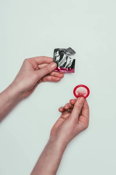 Partial view of woman holding opened condom isolated on grey — Stock Photo