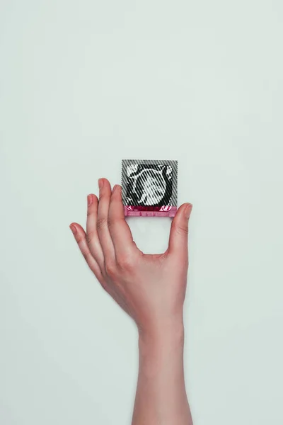 Cropped shot of woman with condom in hand isolated on grey — Stock Photo