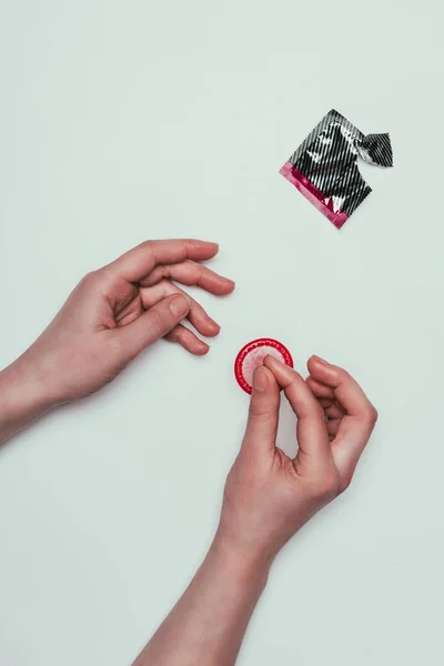 Partial view of woman holding opened condom in hands isolated on grey — Stock Photo