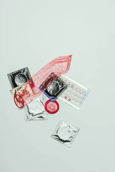 Vue du dessus des pilules contraceptives et des préservatifs isolés sur gris — Photo de stock