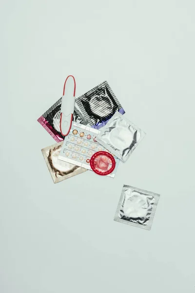 Верхний вид теста на беременность и противозачаточные средства, изолированные на сером — стоковое фото