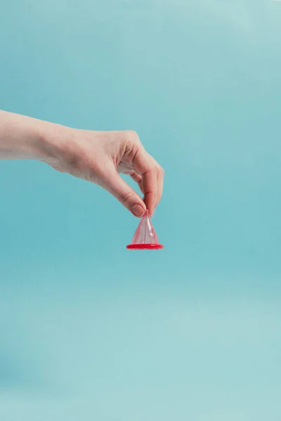 Vue partielle de la femme tenant le préservatif ouvert à la main isolé sur bleu — Photo de stock