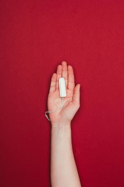 Cropped shot of woman holding tampon in hand isolated on red — Stock Photo