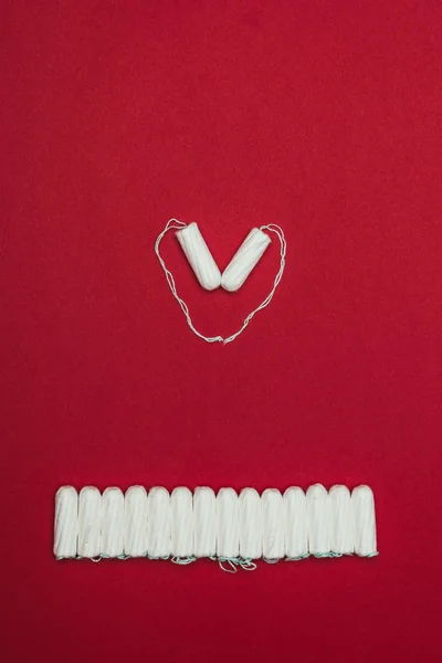 Vista superior de tapones menstruales dispuestos en corazón aislados en rojo - foto de stock