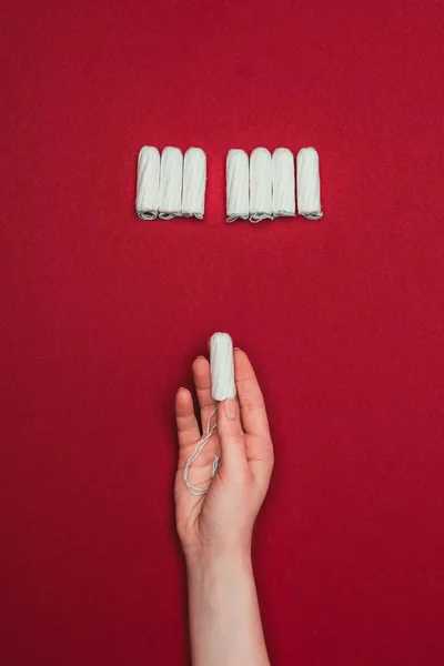 Cropped shot of woman holding tampon in hand isolated on red — Stock Photo