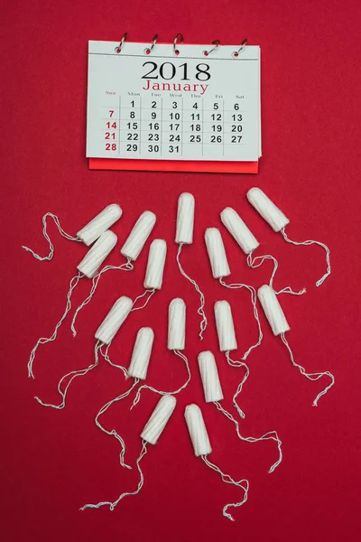 Top view of arranged menstrual tampons and calendar isolated on red — Stock Photo