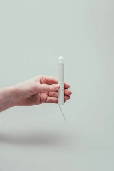 Cropped shot of woman holding tampon in hand isolated on grey — Stock Photo