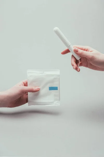 Partial view of women with menstrual pad and tampon in hands isolated on grey — Stock Photo