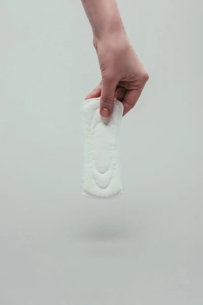 Partial view of woman holding menstrual pad in hand isolated on grey — Stock Photo