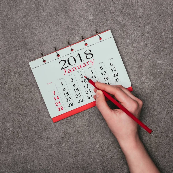 Abgeschnittene Aufnahme einer Frau, die auf Datum in Kalender auf grauer Oberfläche zeigt — Stockfoto