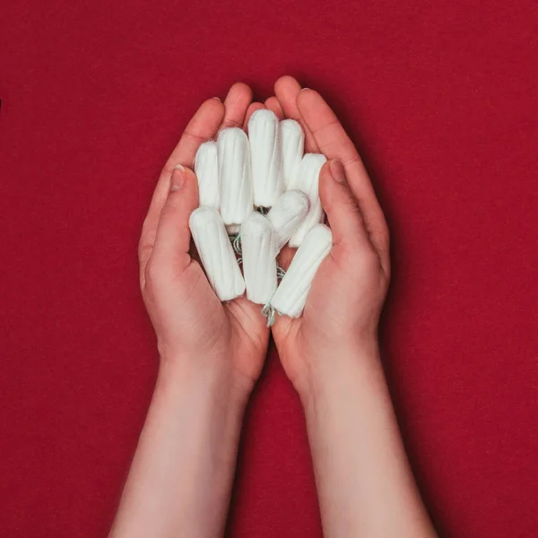 Partial view of woman holding tampons in hands isolated on red — Stock Photo