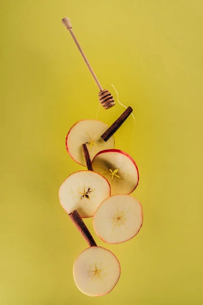 Vista de cerca de los pedazos levitantes de manzana, palitos de canela y miel - foto de stock