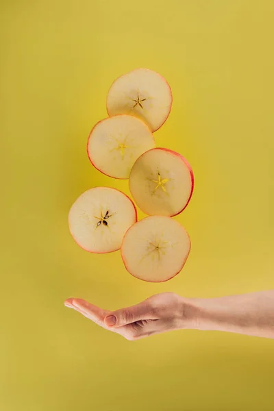 Vista parcial de la mano femenina y piezas levitantes de manzana - foto de stock