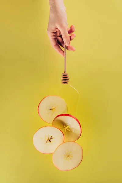 Partial view of female hand and levitating pieces of apple with honey — Stock Photo