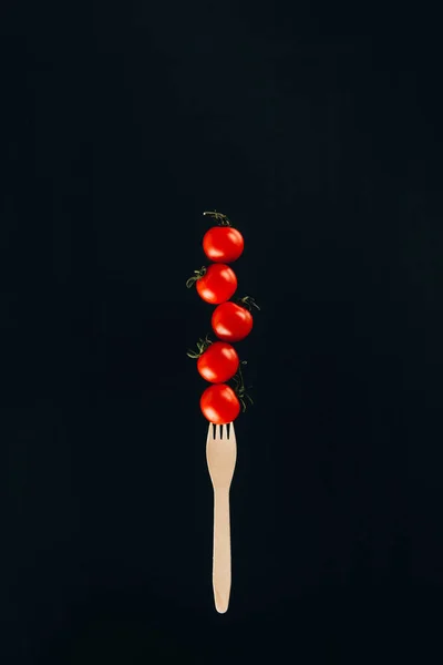 Close up view of levitating cherry tomatoes on fork isolated on black — Stock Photo
