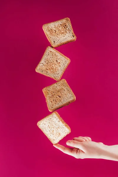 Vista parcial de la mujer sosteniendo tostadas levitantes en el dedo aislado en rosa — Stock Photo