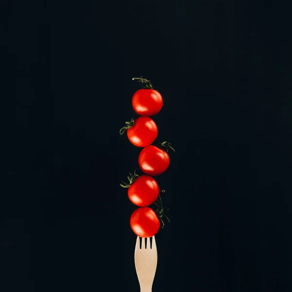 Close up view of levitating cherry tomatoes on fork isolated on black — Stock Photo