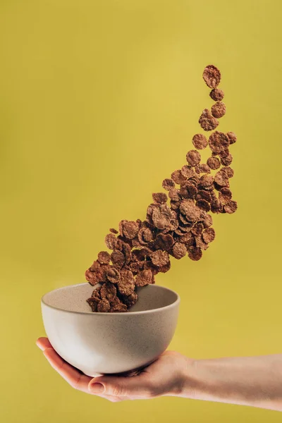 Tiro recortado de mujer sosteniendo tazón con hojuelas de maíz de chocolate levitante - foto de stock