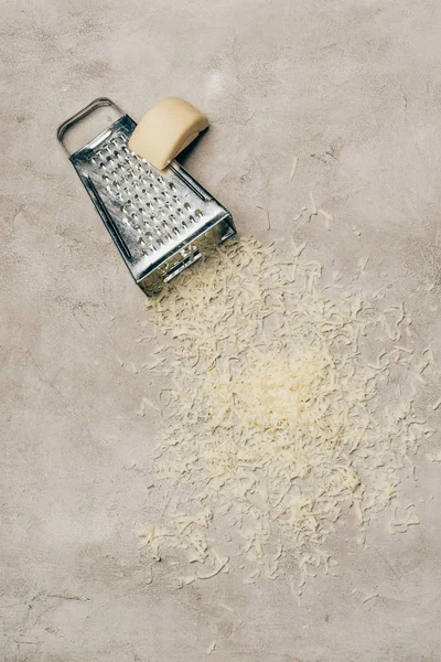 Grater and piece of cheese on light background — Stock Photo