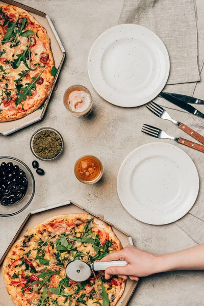 Vista de cerca de la mujer cortando pizza sobre fondo claro - foto de stock