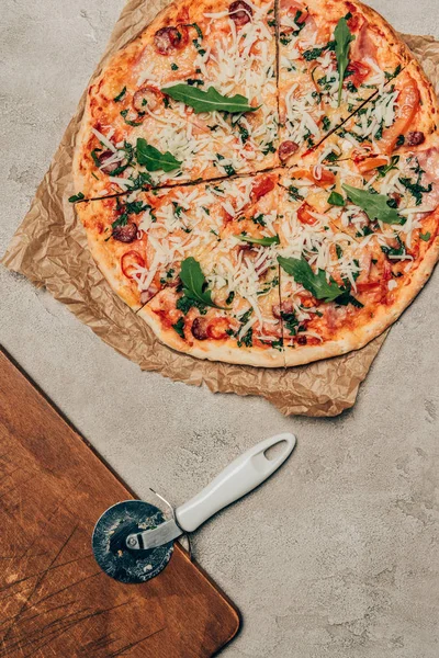 Pizza italiana y cortador de pizza sobre fondo claro - foto de stock