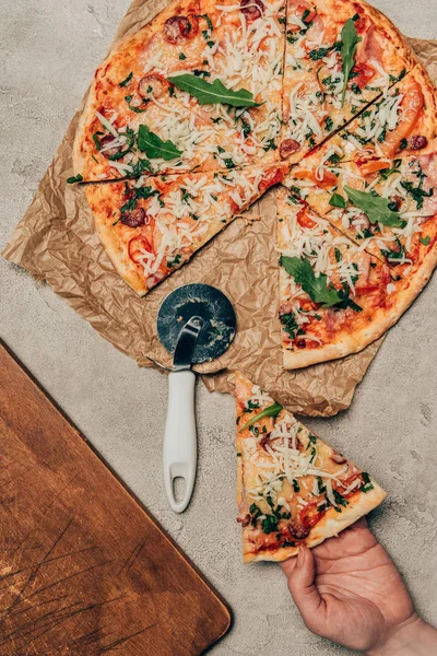 Close-up view of hand taking a slice of pizza on light background — Stock Photo