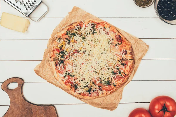 Pizza avec des ingrédients de cuisson sur fond de bois blanc — Photo de stock