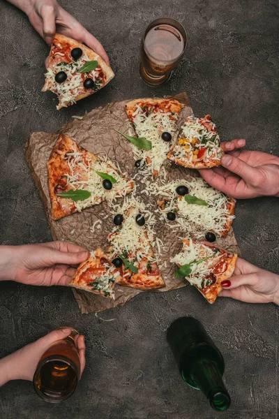 Vista de cerca de la gente en la fiesta tomando rebanadas de pizza sobre fondo oscuro - foto de stock