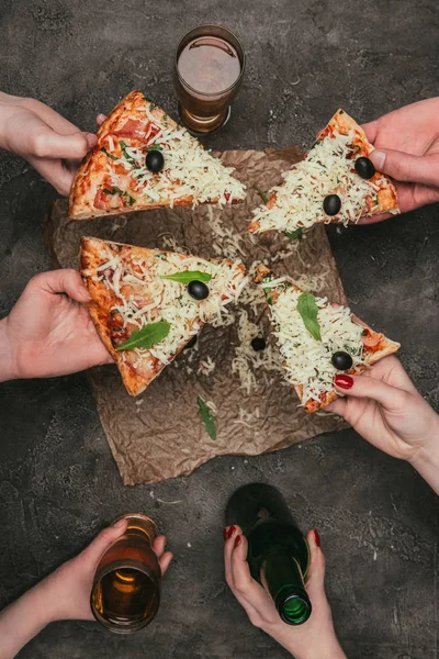 Vista de perto dos amigos que compartilham pizza e bebida no fundo escuro — Fotografia de Stock