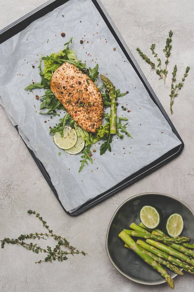 Vue de dessus de viande cuite au four saine avec roquette, citron vert et asperges sur gris — Photo de stock