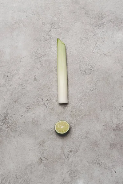 Top view of exclamation mark made from leek and lime on grey — Stock Photo