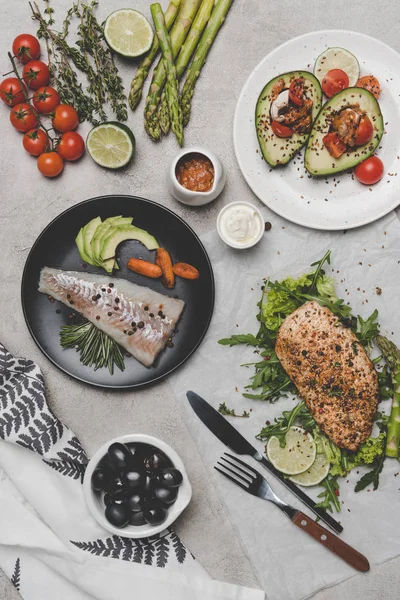 Vista superior de pratos saudáveis com peixe, carne e abacate em cinza — Fotografia de Stock