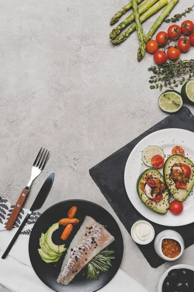 Vista dall'alto di deliziosi piatti sani con pesce e avocado sul grigio — Foto stock