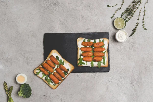 Top view of healthy sandwiches with arugula and roasted baby carrots on slate board — Stock Photo