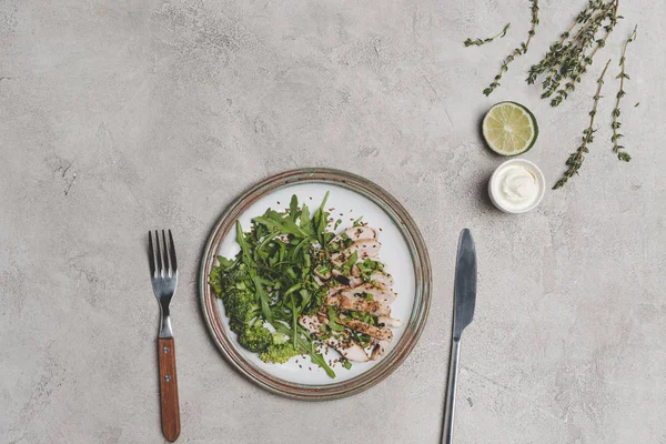 Draufsicht auf gesunde Mahlzeit mit Scheibenfleisch und grünem Gemüse mit Sauce und Limette auf grau — Stockfoto