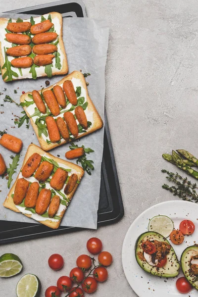 Top view of healthy sandwiches with baby carrots and arugula on grey — Stock Photo