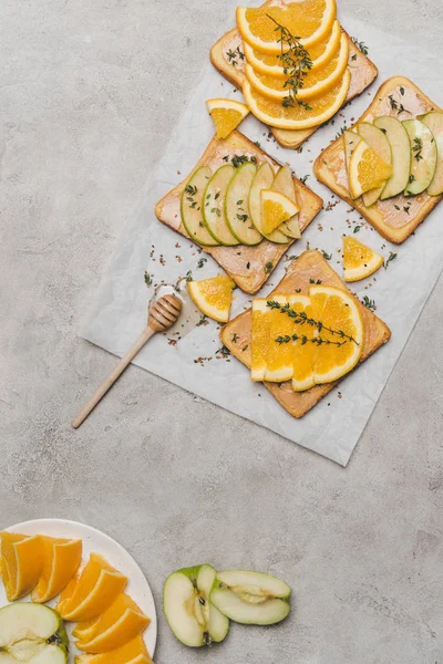 Vista superior de sándwiches saludables con frutas frescas y miel en gris - foto de stock