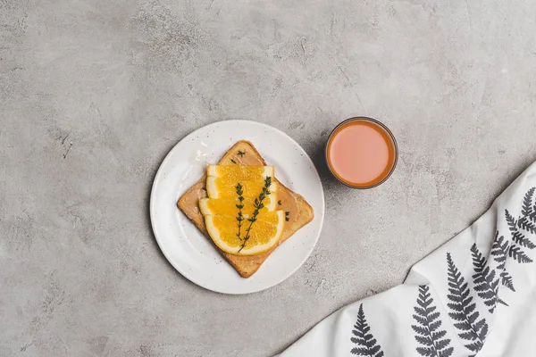 Sandwich with honey and orange slices and glass of fresh juice on grey — Stock Photo