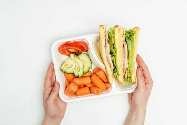 Cropped image of woman holding lunch box with sandwiches isolated on white — Stock Photo