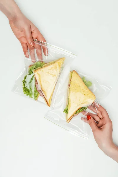 Image recadrée de femmes prenant des sandwichs dans des sacs ziplock isolés sur blanc — Photo de stock