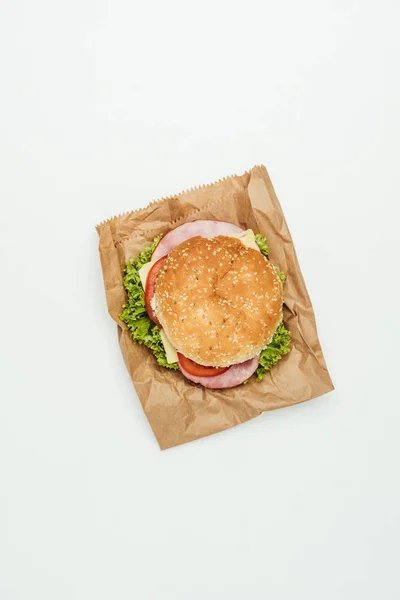 Vista dall'alto di hamburger con carne e verdure su sacchetto di carta isolato su bianco — Foto stock