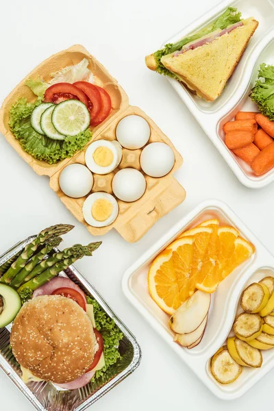 Top view of fruits and vegetables in lunch boxes isolated on white — Stock Photo