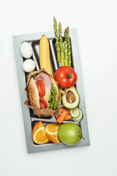 Vista dall'alto del vassoio con hamburger, verdure e frutta isolati su bianco — Foto stock