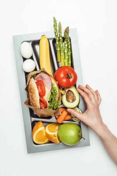 Cropped image of woman taking avocado from tray with food isolated on white — Stock Photo