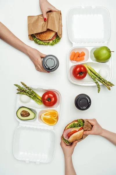 Abgeschnittenes Bild von Frauen, die Take-away-Burger essen und Kaffee trinken, um in die Isolation zu gehen — Stockfoto