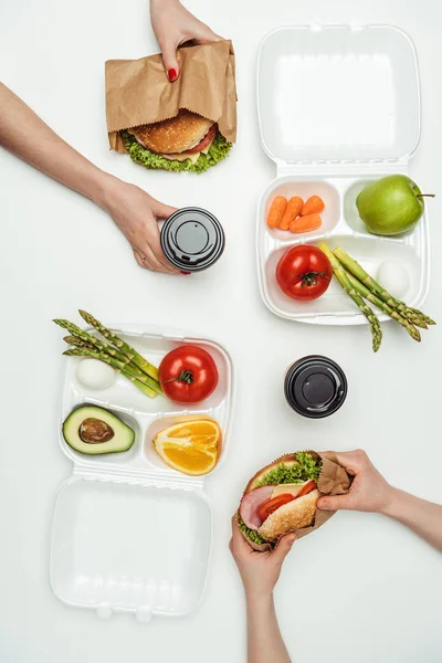 Image recadrée de femmes mangeant des hamburgers à emporter et buvant du café pour aller isolé sur blanc — Photo de stock